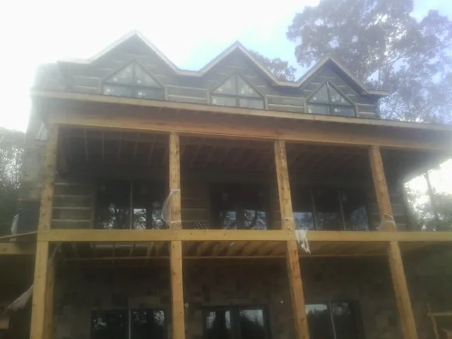 Dormers and porch framing on a large log home under construction — Roof Coating work by our crew in Saint Cloud