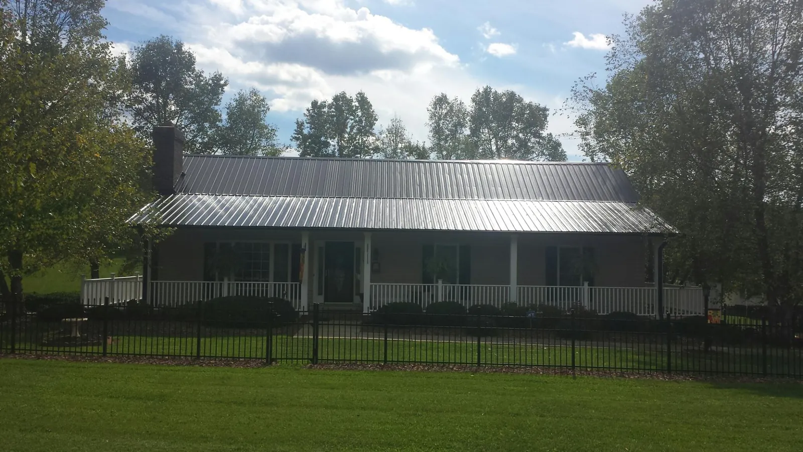 Gray metal roof on a brick ranch with a full width front porch — Gutter Guard Installation work by our crew in Saint Cloud